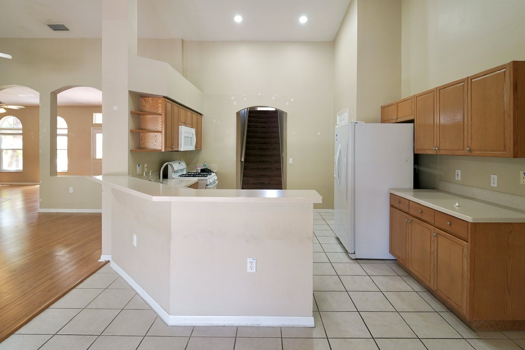 Kitchen before the remodel: oak cabinets, a white tile floor, and a raised peninsula dividing the room.