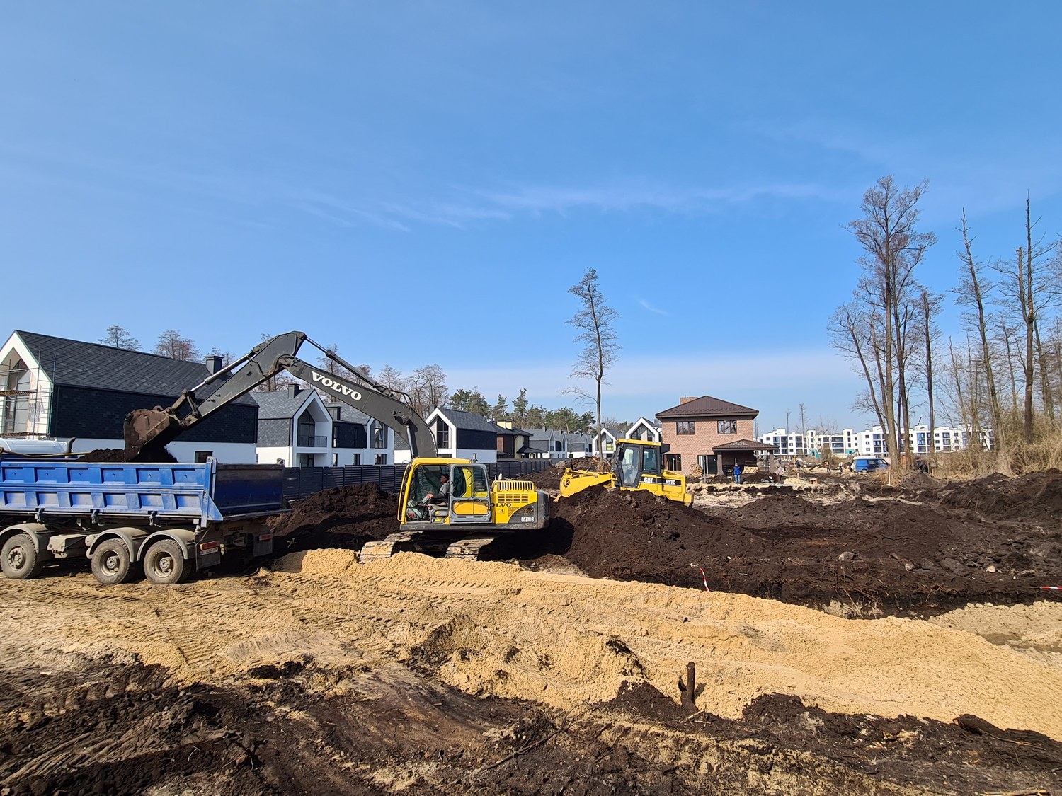 Excavator and dump truck clearing raw ground for the townhouse development, before foundations.