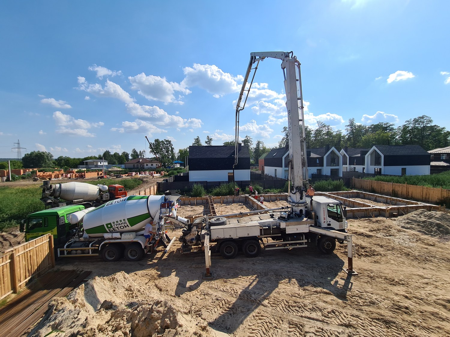 Concrete pump truck pouring foundations for a row of townhouses, formwork and rebar visible.