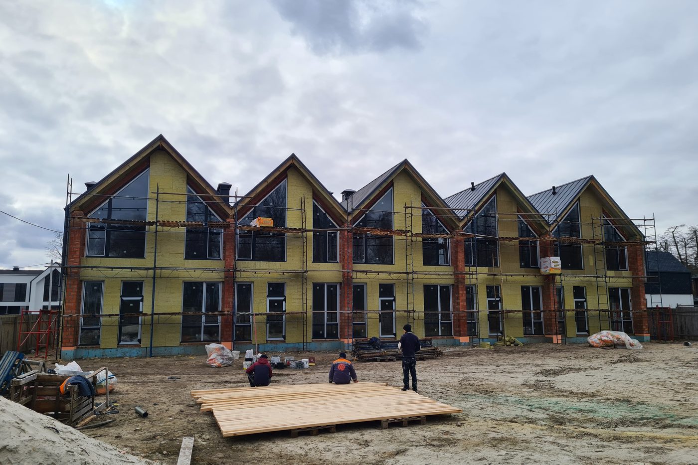 Insulation boards fixed across the townhouse elevation, workers on site.