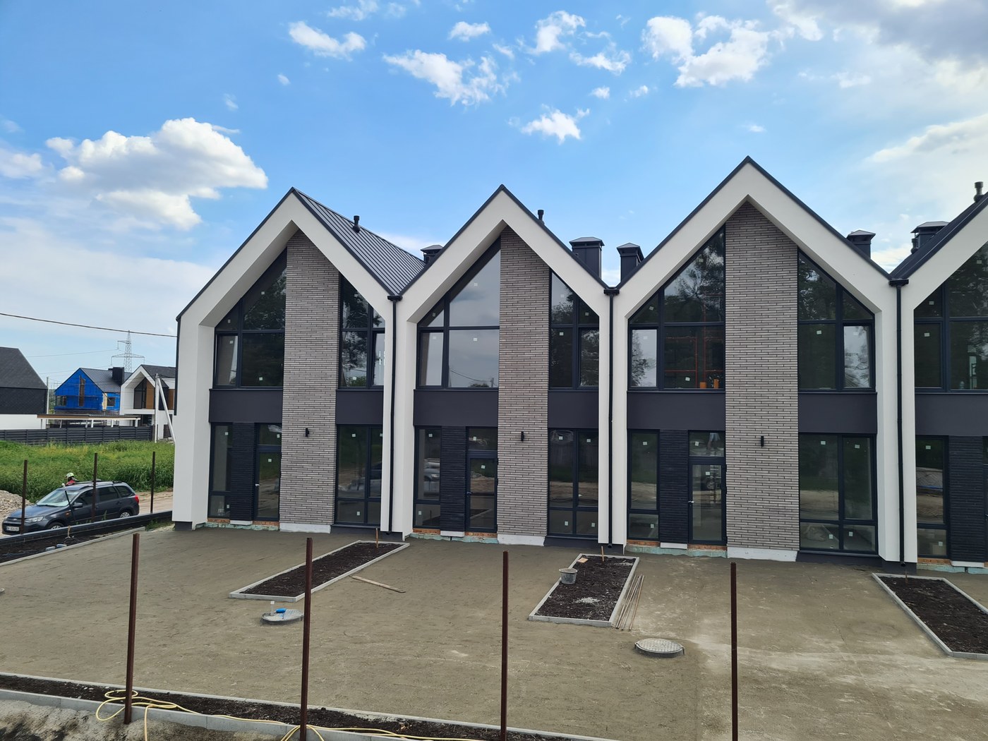 Completed townhouse facades with paved courtyard finished and planting beds not yet planted.