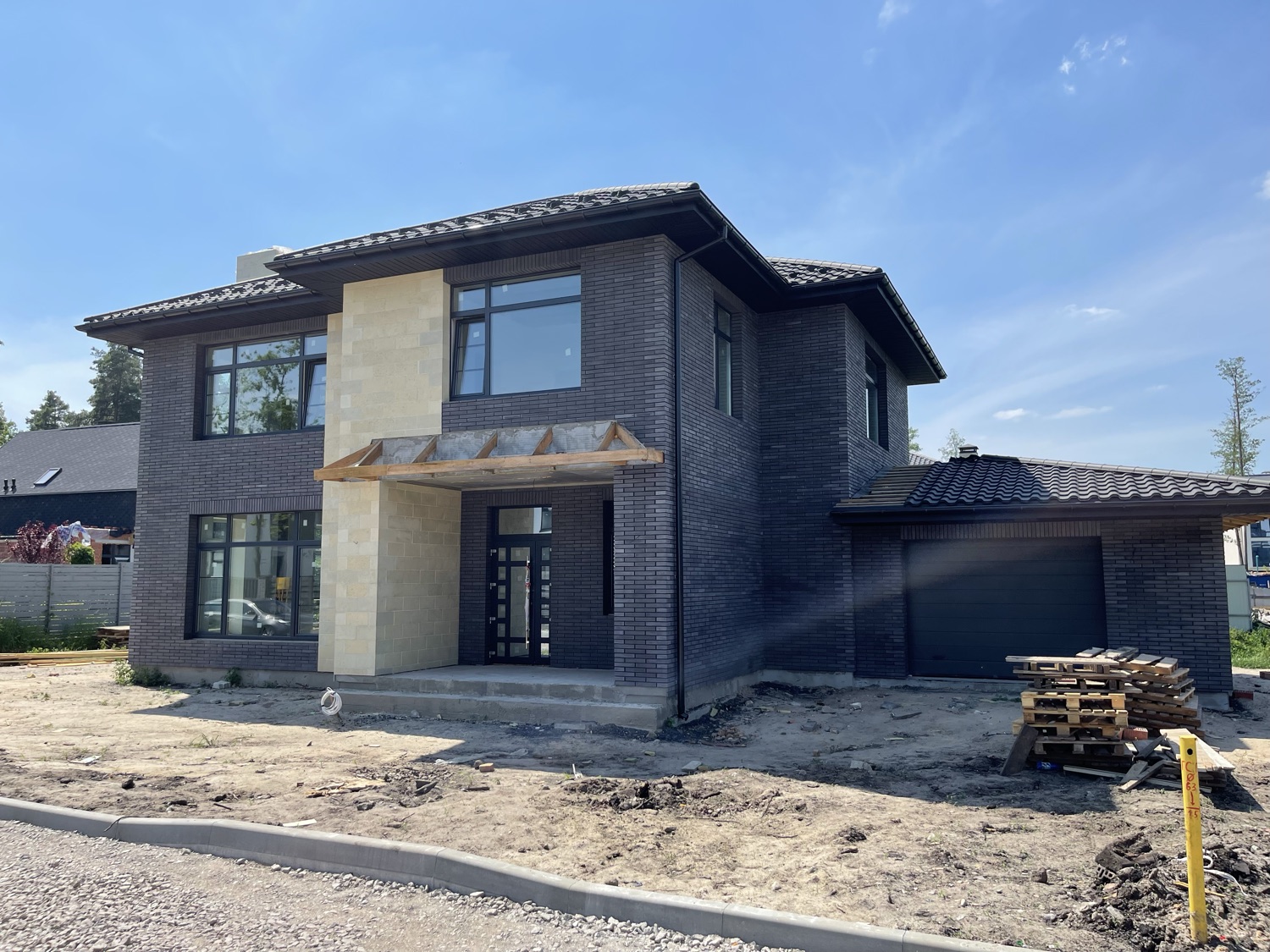 Dark face brick and stone accent cladding being applied to the exterior, still under construction.