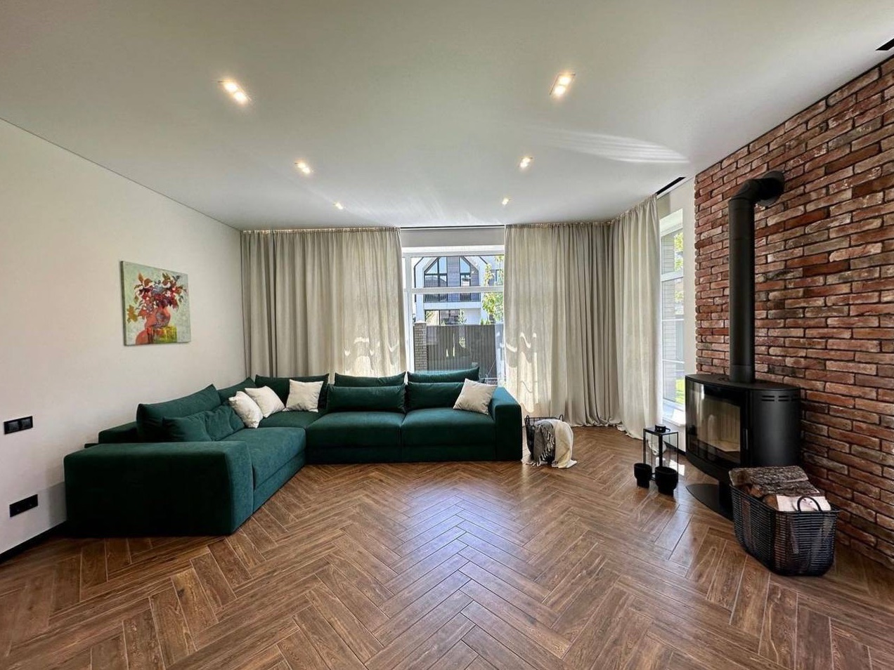 Finished living space with a brick feature wall, wood-burning stove, and sectional seating.