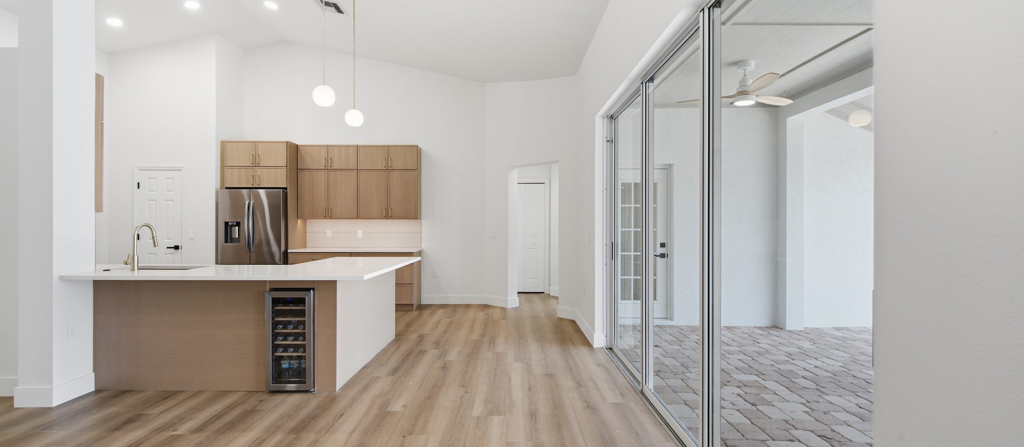 Open kitchen and living area with sliding glass doors leading to a paved outdoor space.