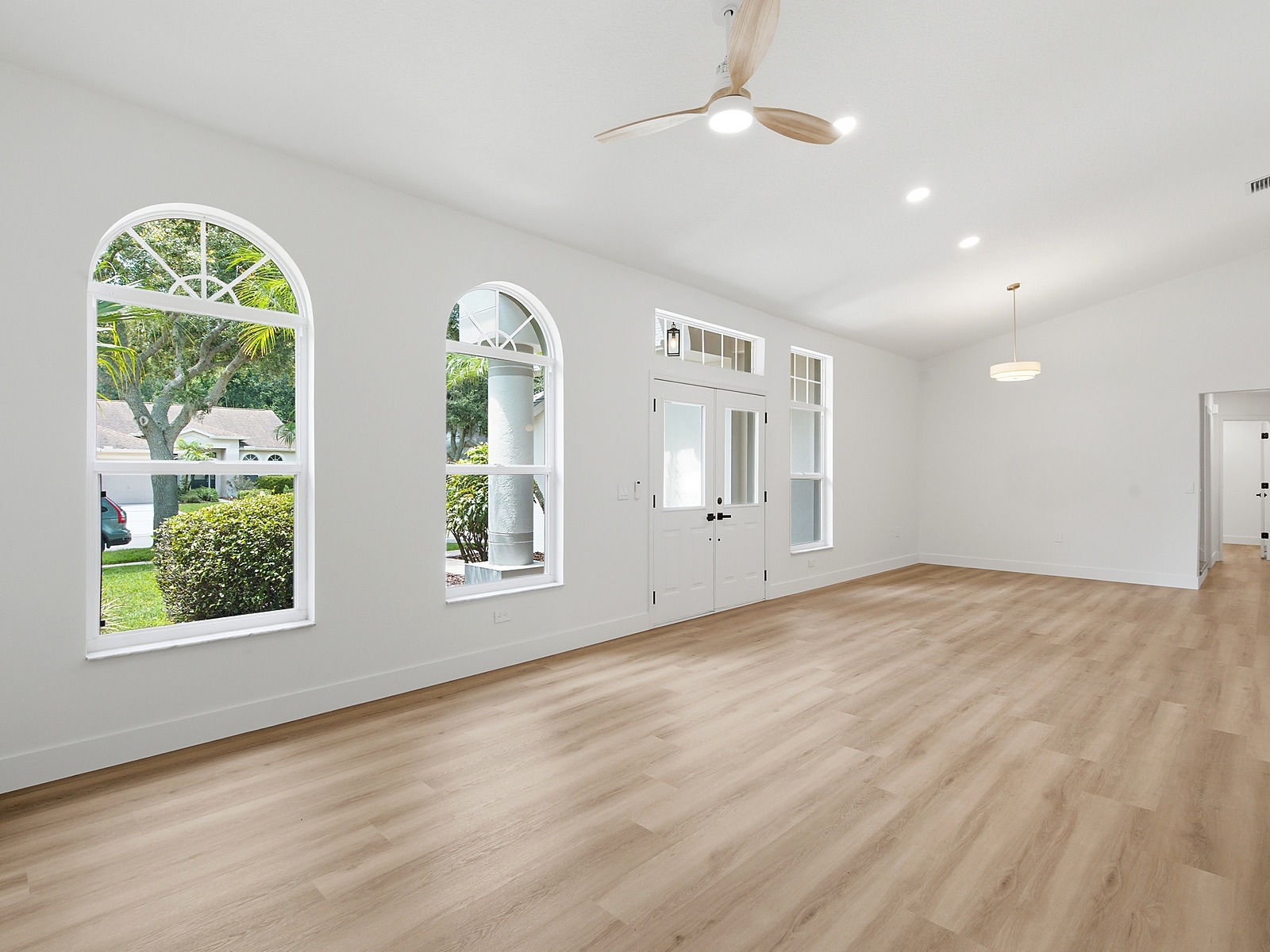 Renovated great room with vaulted ceilings, arched windows, and the front entry.