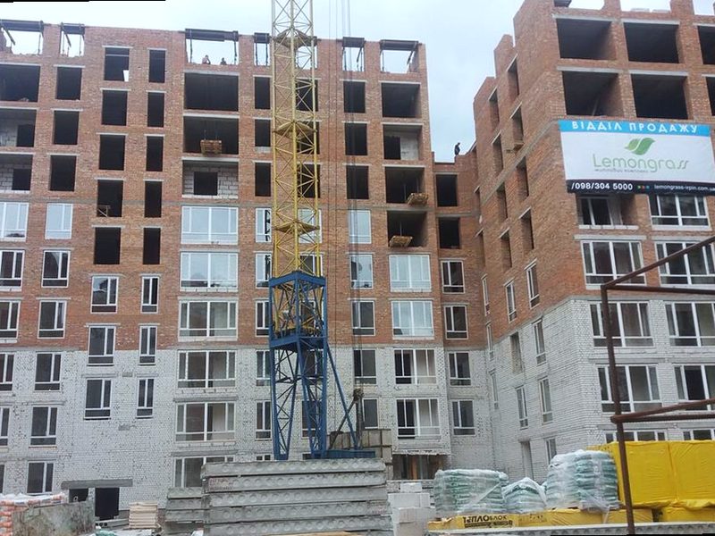 The structure at full height: ten stories of brick, windows fitted on the lower floors, a tower crane in front.