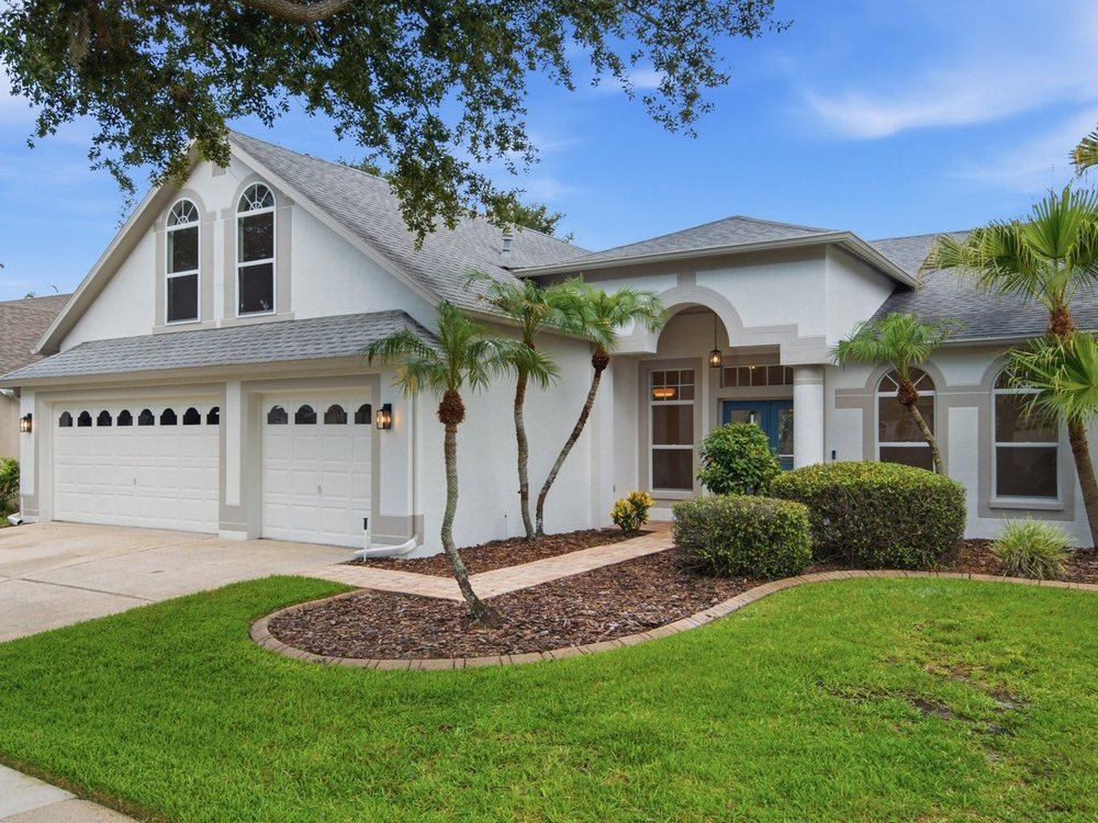 Renovated Florida home exterior with palms, arched windows and a tile roof.