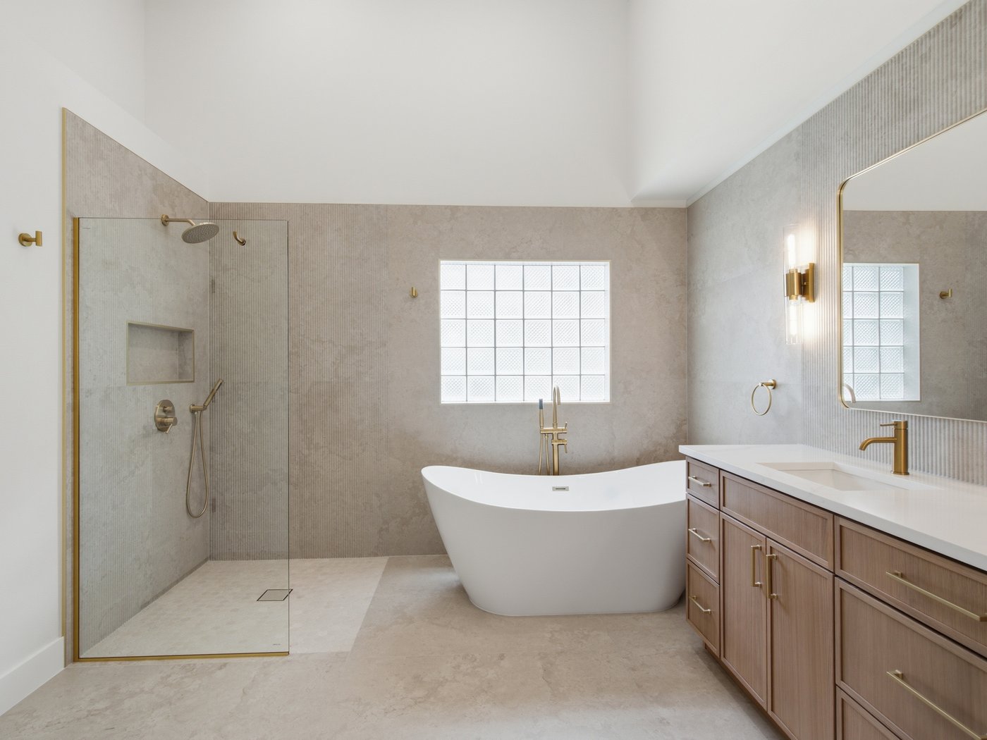 Renovated primary bathroom with a freestanding tub, glass-block window, and floating double vanity.