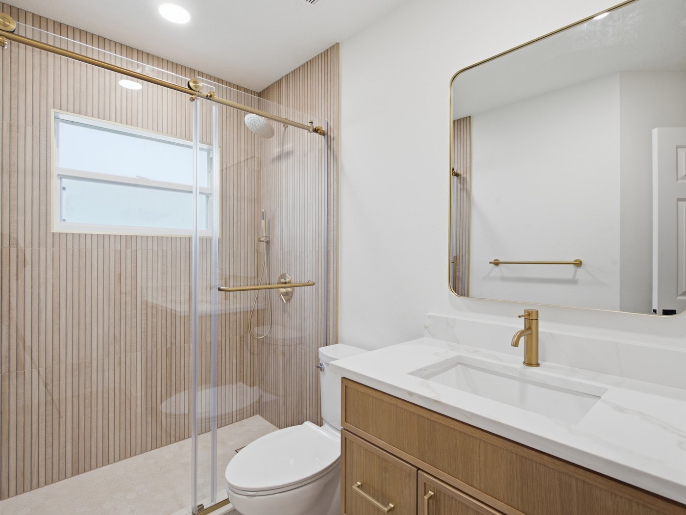 Renovated secondary bathroom with a fluted-glass walk-in shower and floating vanity.