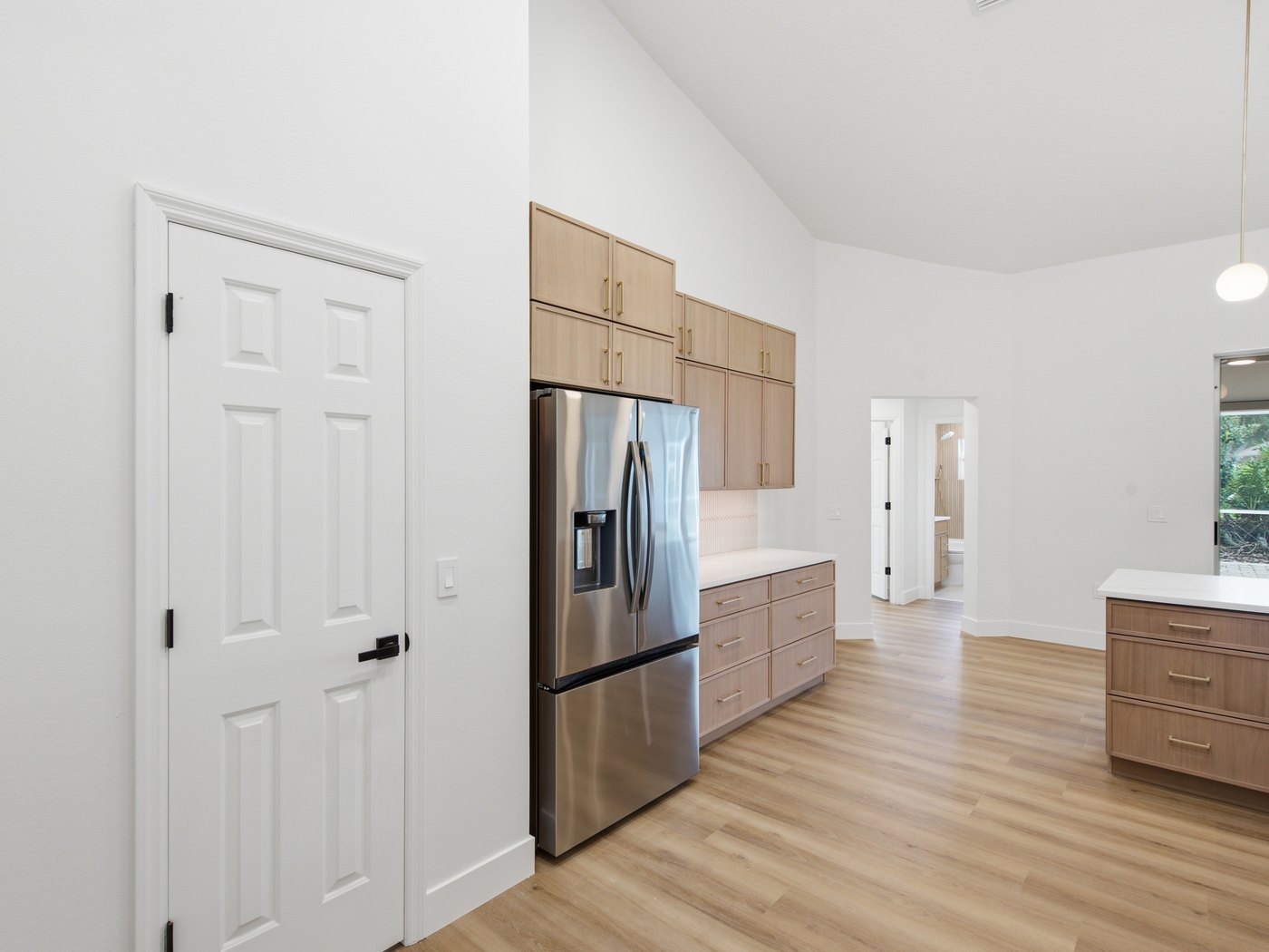 The kitchen from the hallway: full-height oak cabinets running to the ceiling, a panelled refrigerator built into the run, and the island beyond.