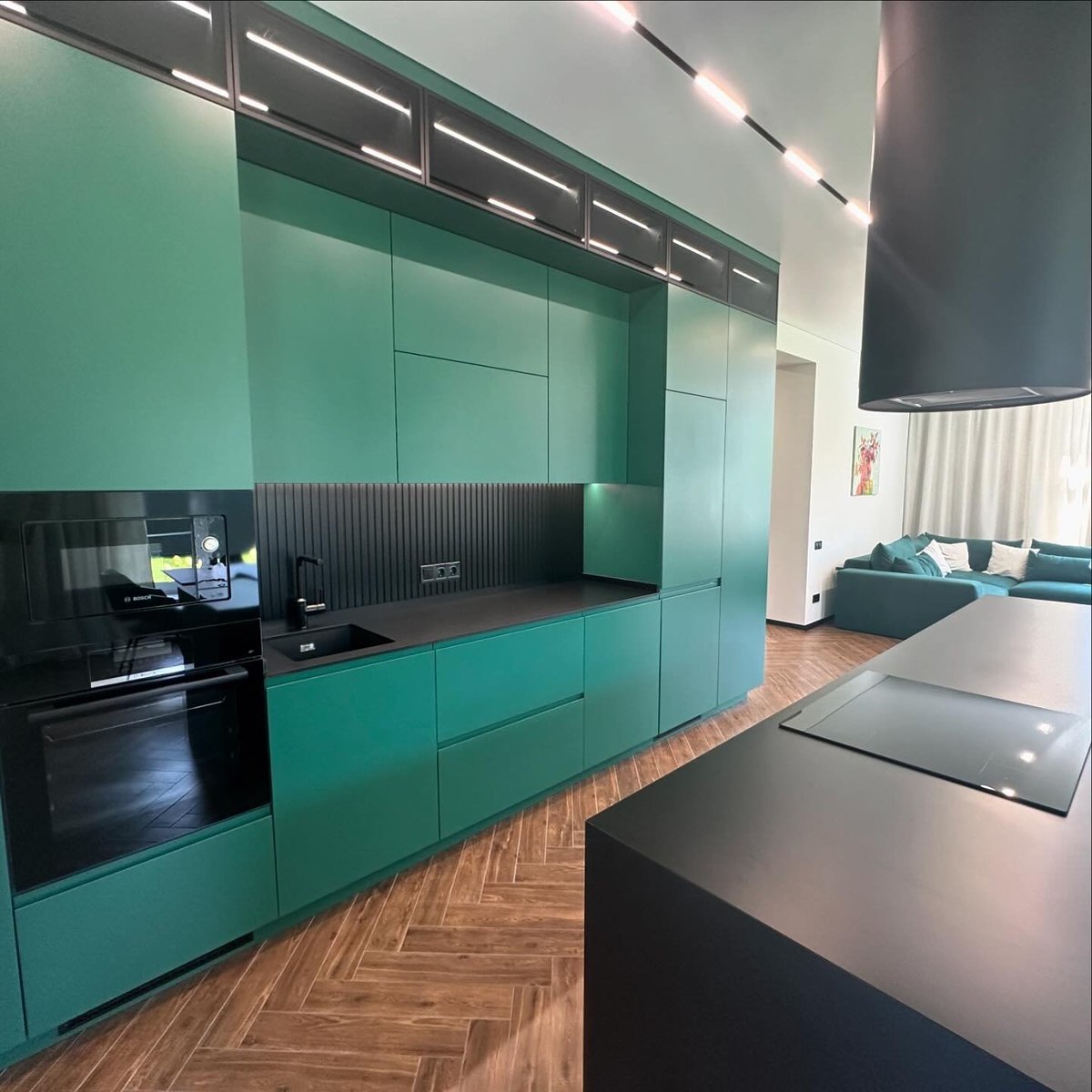 Finished kitchen with full-height emerald cabinetry, integrated appliances, and a black waterfall island.