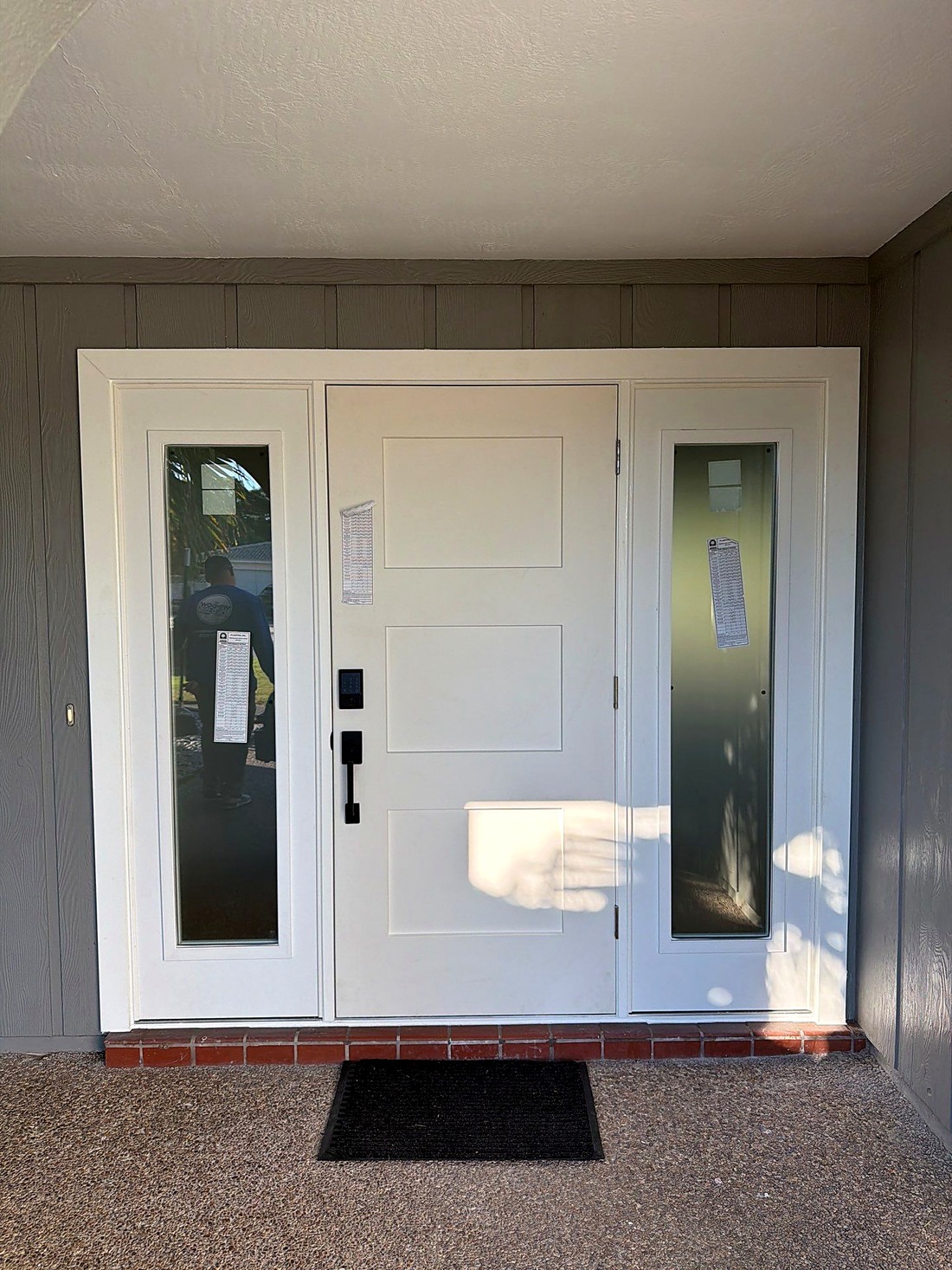 Finished impact-rated entry door with glass sidelights, viewed from the front porch.