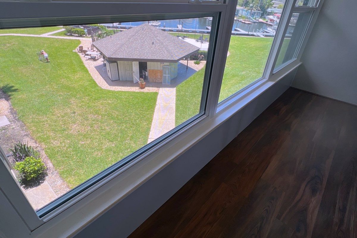A corner window looking down onto a lawn and a gazebo, wood floor running to the sill.