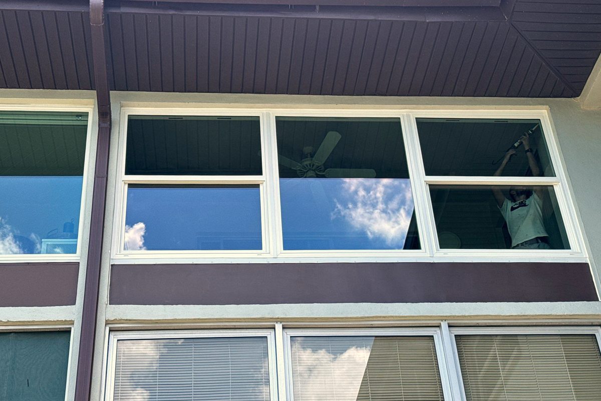 Two floors of impact windows on a waterside elevation, sky reflected in the upper glass.
